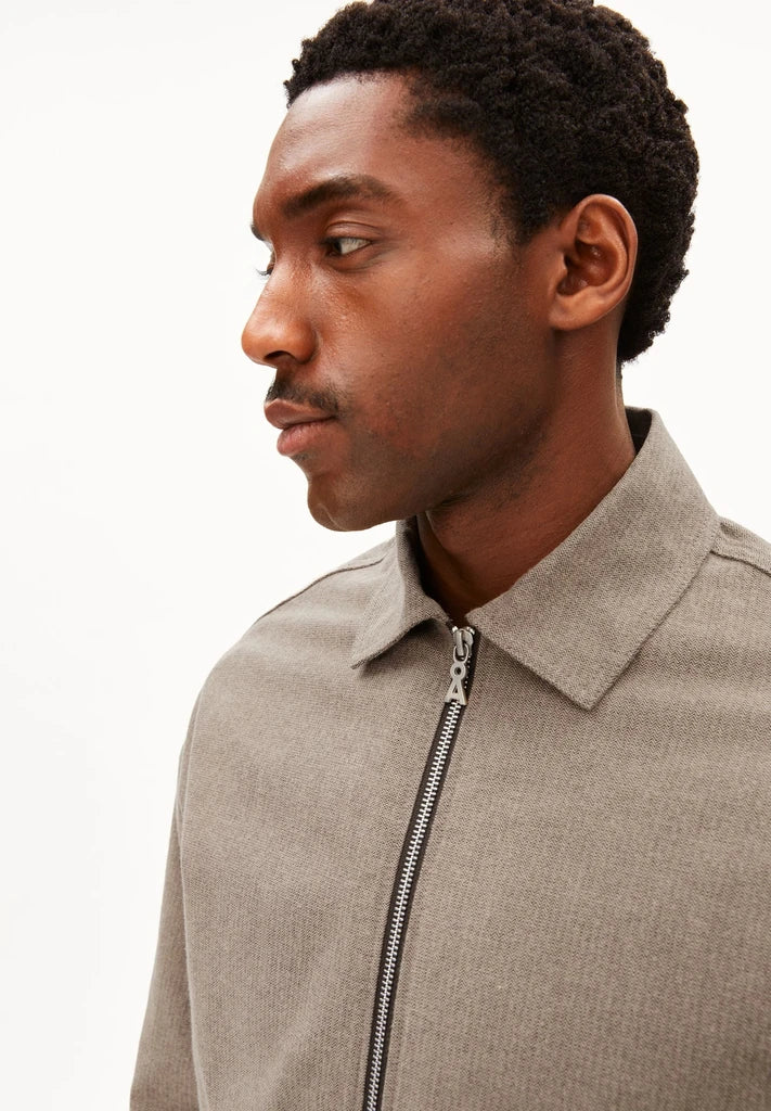 Close-up side profile of a man wearing ARMEDANGELS Canada Structured Jacket in Honey Reed, showing the shirt collar, metal zip and fine stripe texture, against a white background.
