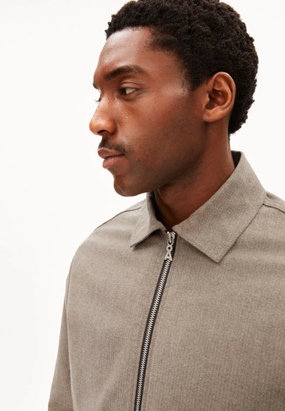 Close-up side profile of a man wearing ARMEDANGELS Canada Structured Jacket in Honey Reed, showing the shirt collar, metal zip and fine stripe texture, against a white background.