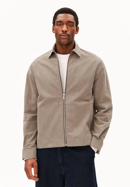 Man wearing ARMEDANGELS Canada Structured Jacket in Honey Reed over a white tee with dark navy jeans, front view against a white background.