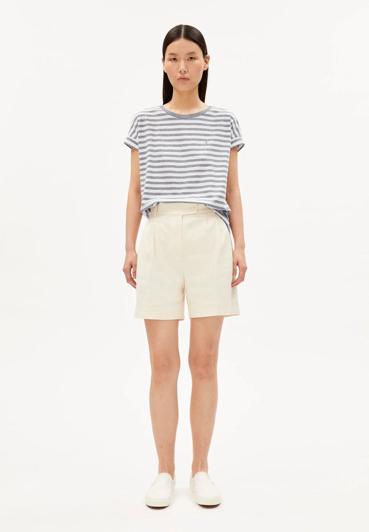 Woman wearing a striped shirt and cream shorts on a white background