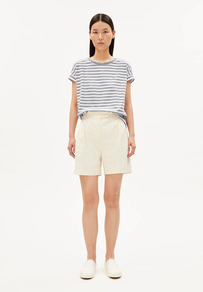 Woman wearing a striped shirt and cream shorts on a white background
