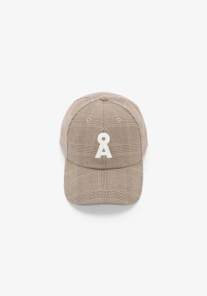 A beige plaid baseball cap featuring a white embroidered patch on the front, set against a plain white background.