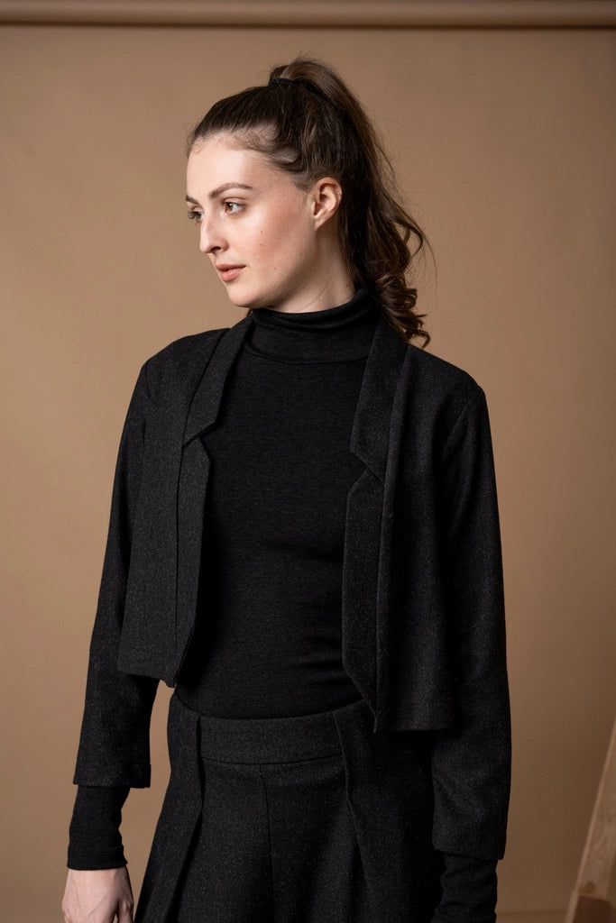 Close-up of the Bodybag by Jude Nassau Jacket in Charcoal, showing the sculptural notch detail framing the neckline and the soft brushed surface of the fabric.