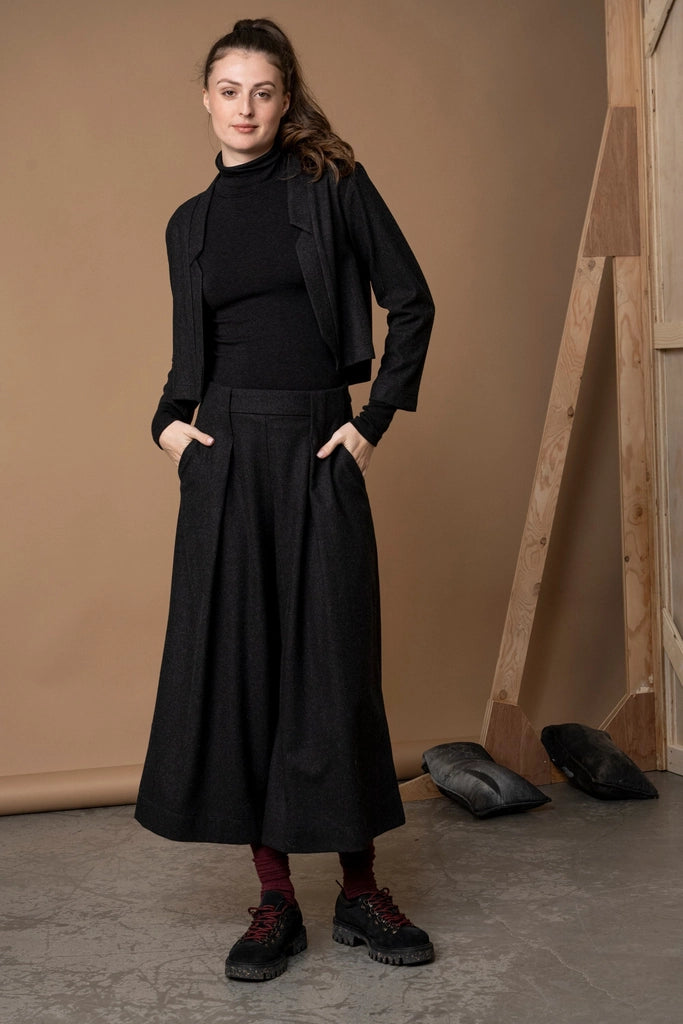 Woman in the Bodybag by Jude Nassau Jacket in Charcoal with her hands in her trouser pockets, showing the cropped length sitting at the waist.