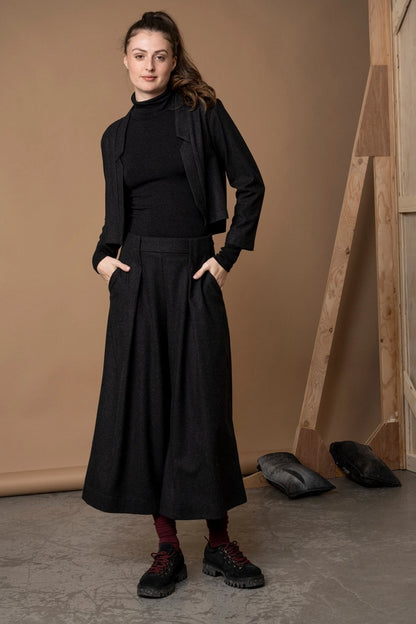 Woman in the Bodybag by Jude Nassau Jacket in Charcoal with her hands in her trouser pockets, showing the cropped length sitting at the waist.