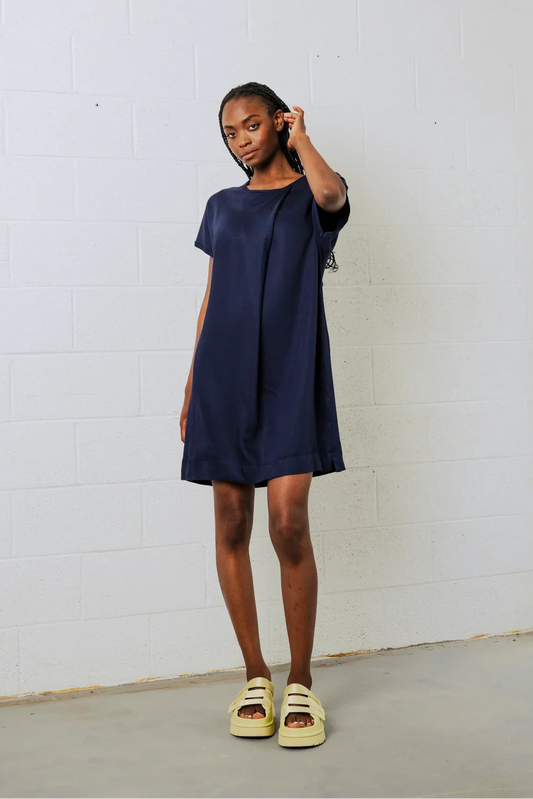 Woman wearing a navy blue dress against a white wall