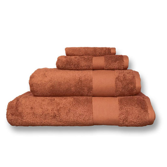A set of four terracotta-colored bath towels in different sizes, neatly stacked in a pyramid on a white background.