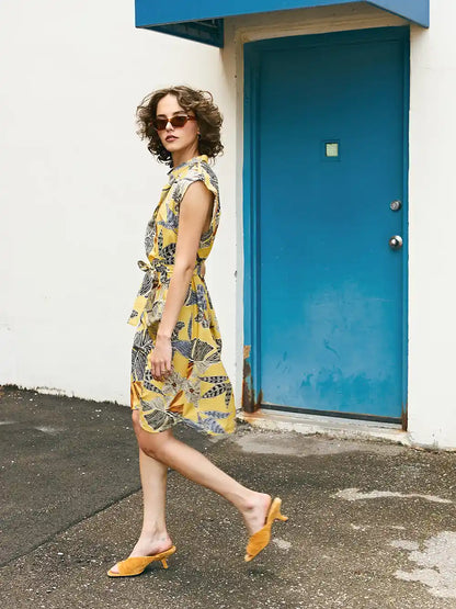 Woman in a floral dress walking past a blue door.