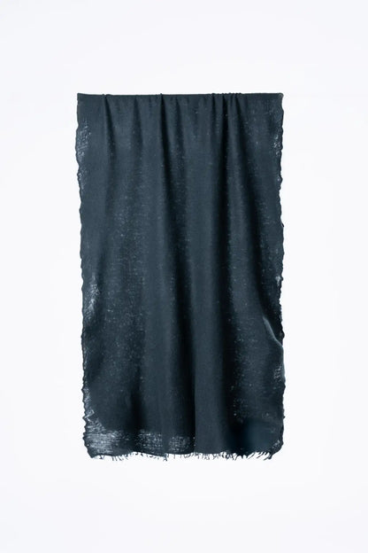 A dark peacock green scarf with a subtle textured pattern and frayed edges, hanging against a plain white background.