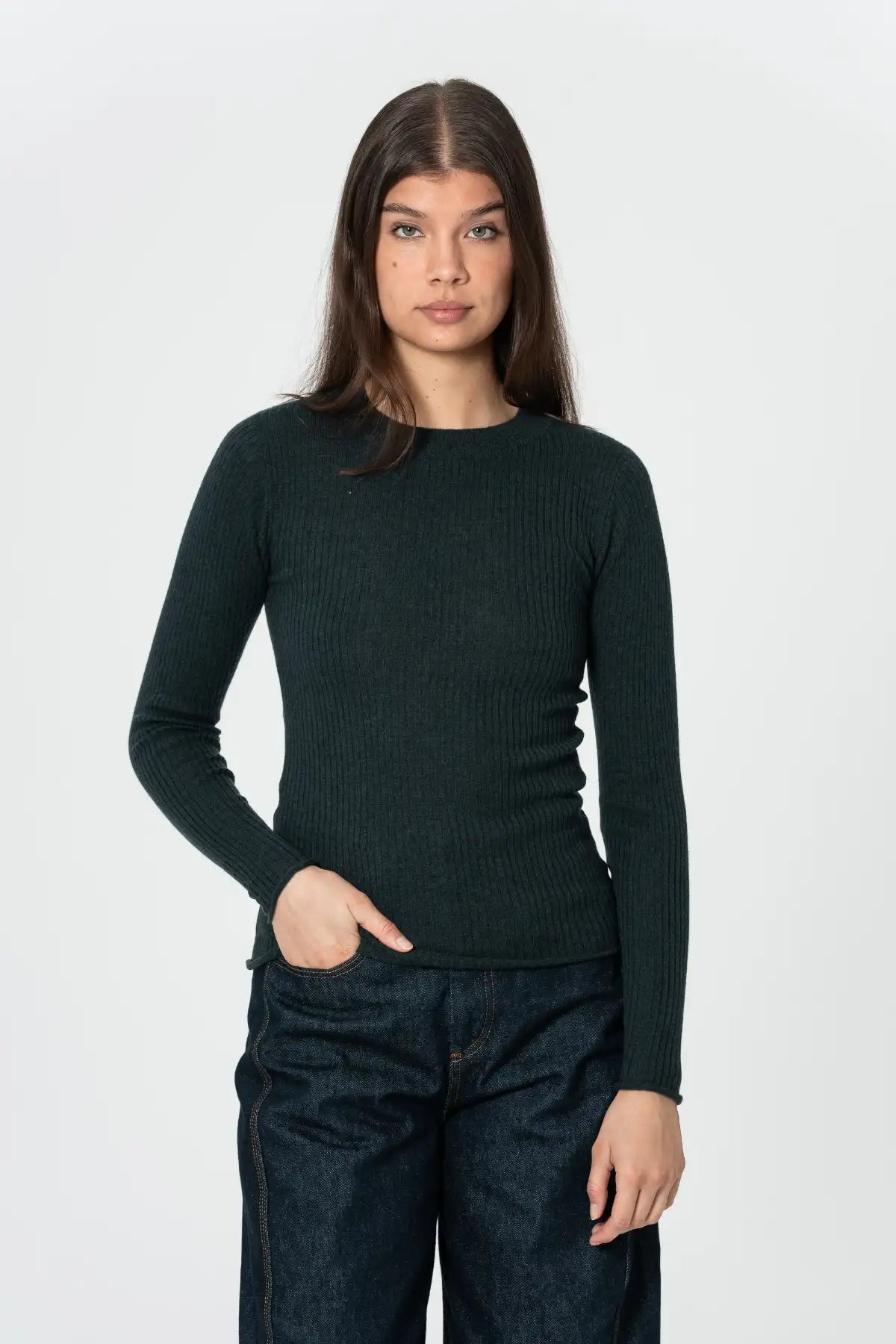 Person wearing a dark green sweater and dark pants on a white background