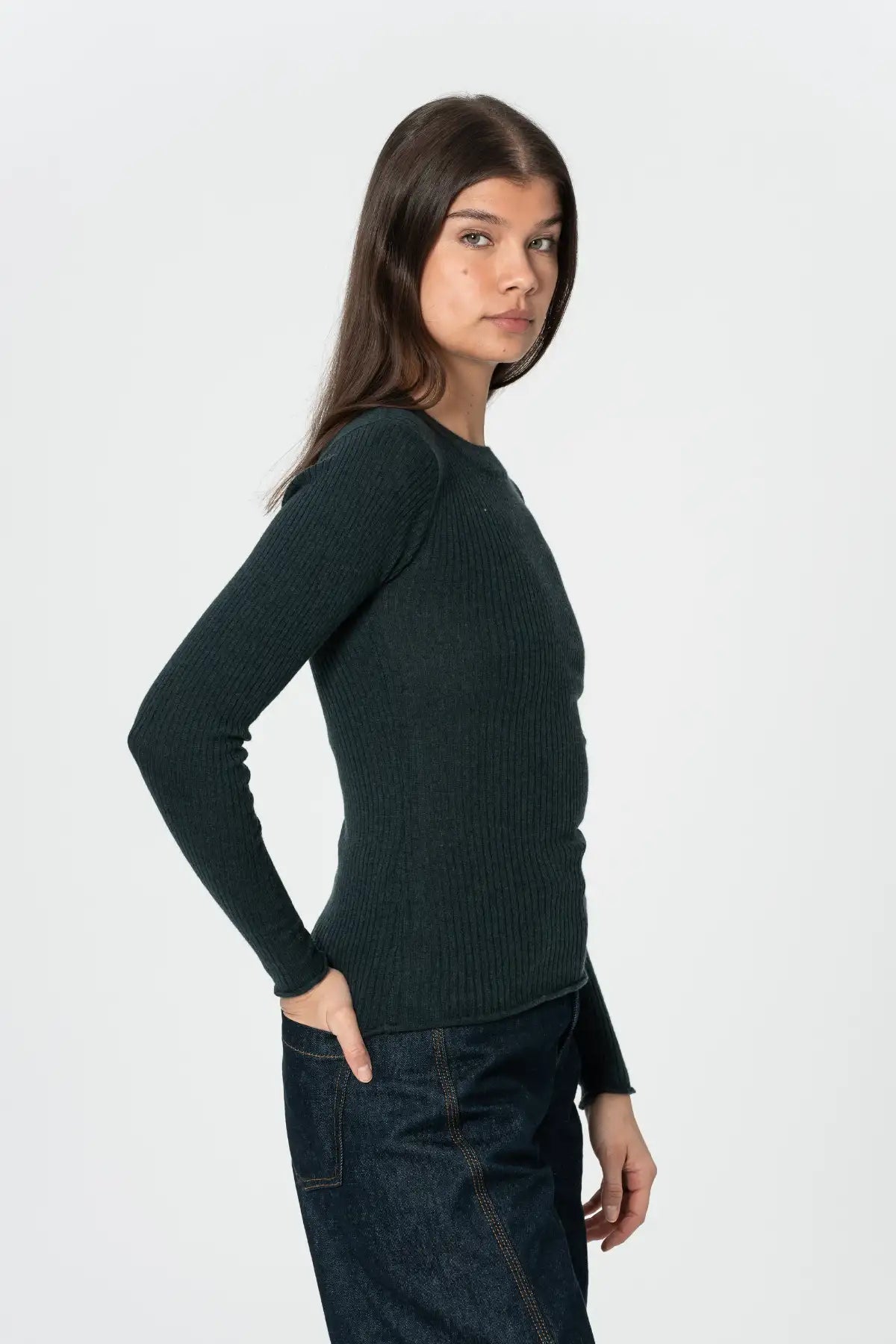 Woman wearing a dark green sweater and jeans on a white background