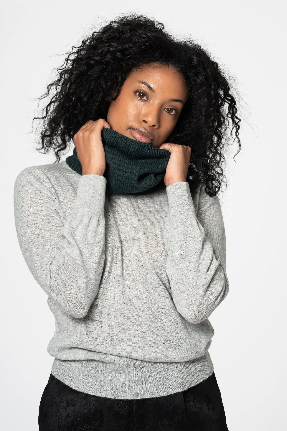 Dinadi merino wool neckwarmer in dark green worn by a woman in a grey sweater for added warmth in Kelowna