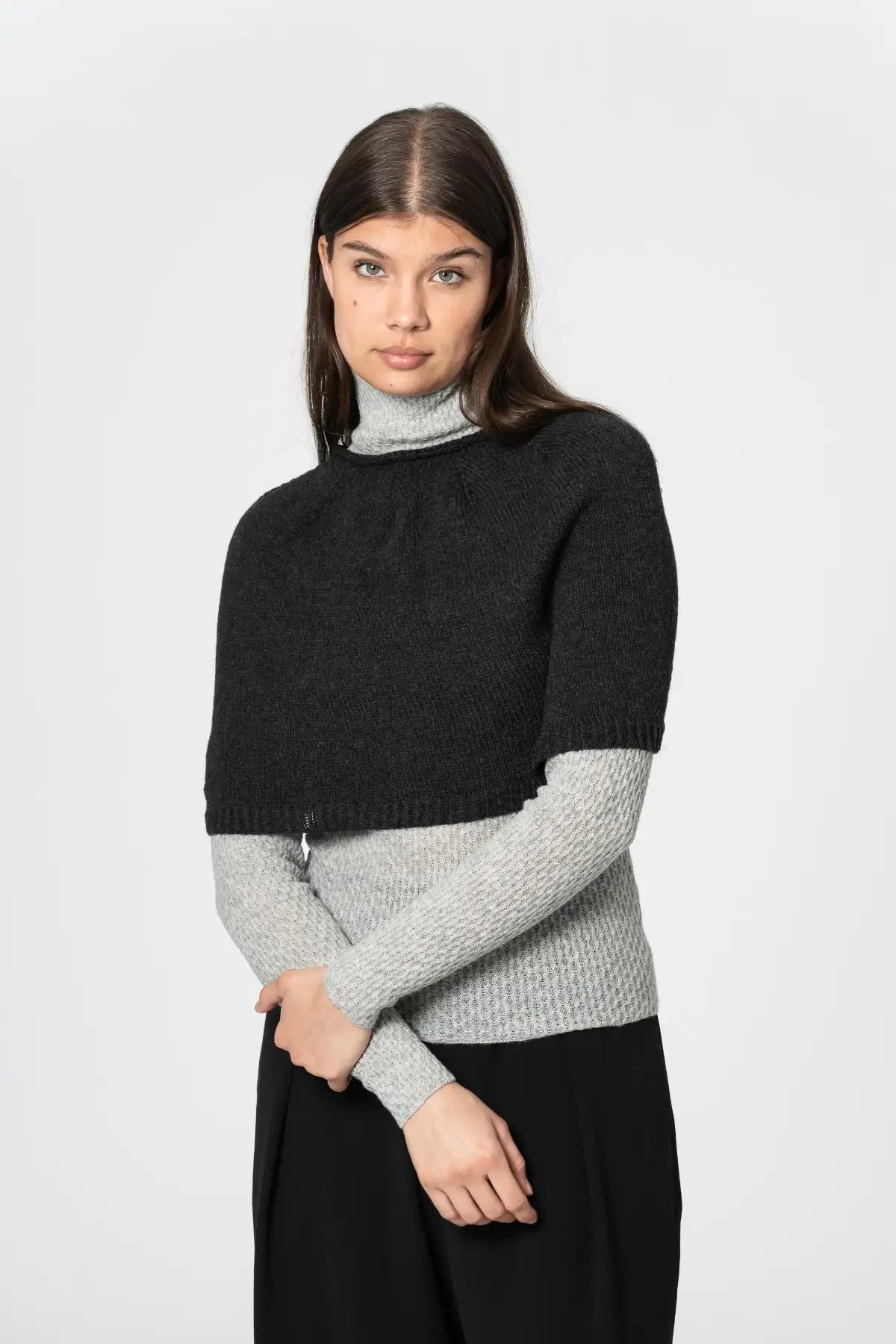 Dinadi black poncho designed for warmth and style, layered over a light turtleneck sweater in Kelowna and Canada