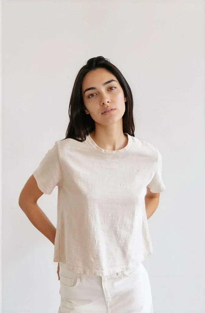 Woman wearing a plain cream t-shirt against a white background