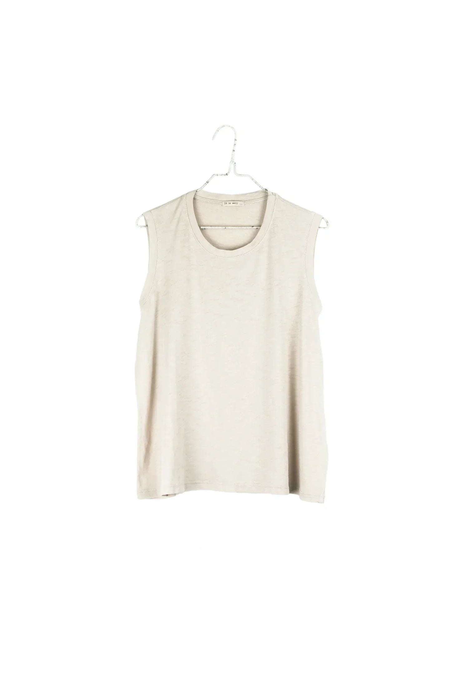 A sleeveless crewneck top in a light cream or off-white color, hanging on a white plastic hanger against a plain white background.