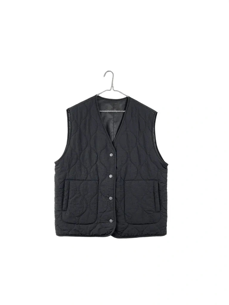 A black quilted sleeveless vest with snap-button front and two front patch pockets, hanging on a metal hanger against a plain white background.