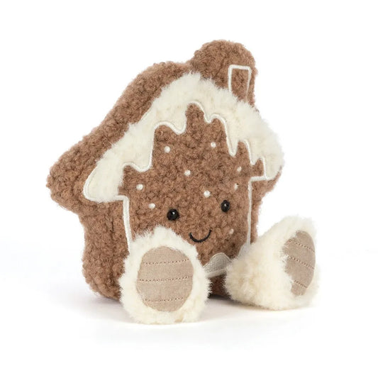 Jellycat Amuseables Molasi Cookie plush at an angle: a curly brown gingerbread house cookie with fluffy cream icing on the roof, white dot details, a smiling face and fluffy-cuffed feet.