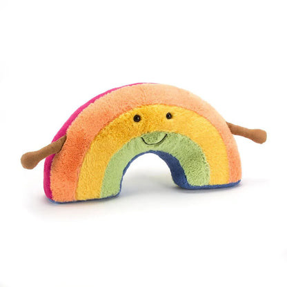 A plush rainbow toy with a smiling face, featuring soft fuzzy stripes in pink, orange, yellow, green, blue, and purple, with small brown arms, photographed on a clean white background.
