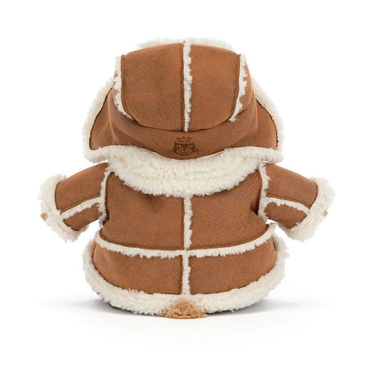 Back view of the Jellycat Bartholomew Bear Alpine, showing the tan coat with cream seam trim, the hood of the trapper hat with an embroidered Jellycat logo and a little tail peeking out.