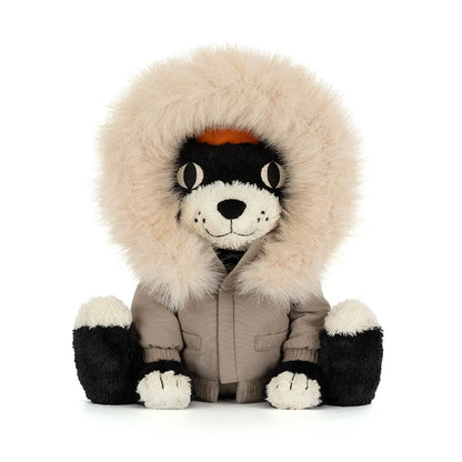 Front view of Jellycat Jack Alpine sitting upright, peeking out from a fluffy cream fur-trimmed hood, in a taupe parka with pockets and ribbed cuffs, with black and cream paws.