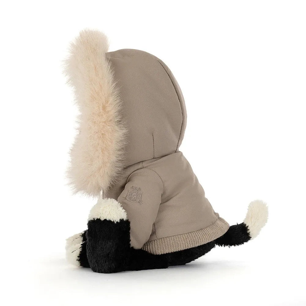 Side view of Jellycat Jack Alpine, showing the taupe parka hood with its fluffy cream trim, an embroidered Jellycat logo on the sleeve and a cream-tipped tail.
