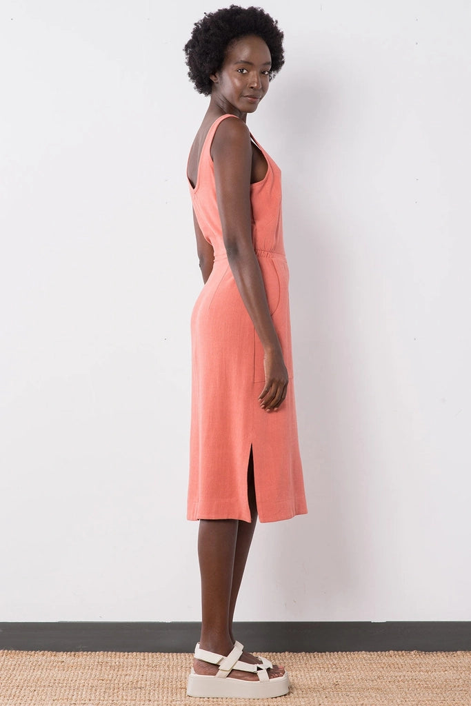 Side view of the Jennifer Glasgow Design Aisha Dress in Terracotta, showing the scoop back, the gathered waist and the side slit at the hem.