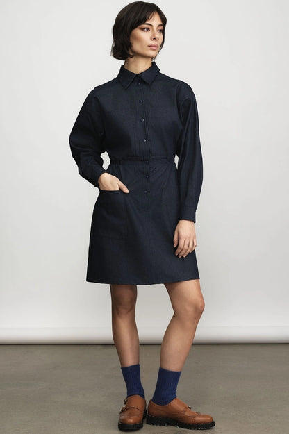 Woman wearing the Jennifer Glasgow Design Celeste Shirt Dress in dark denim with a button front and shirt collar, styled with navy socks and brown leather loafers against a light grey studio background.