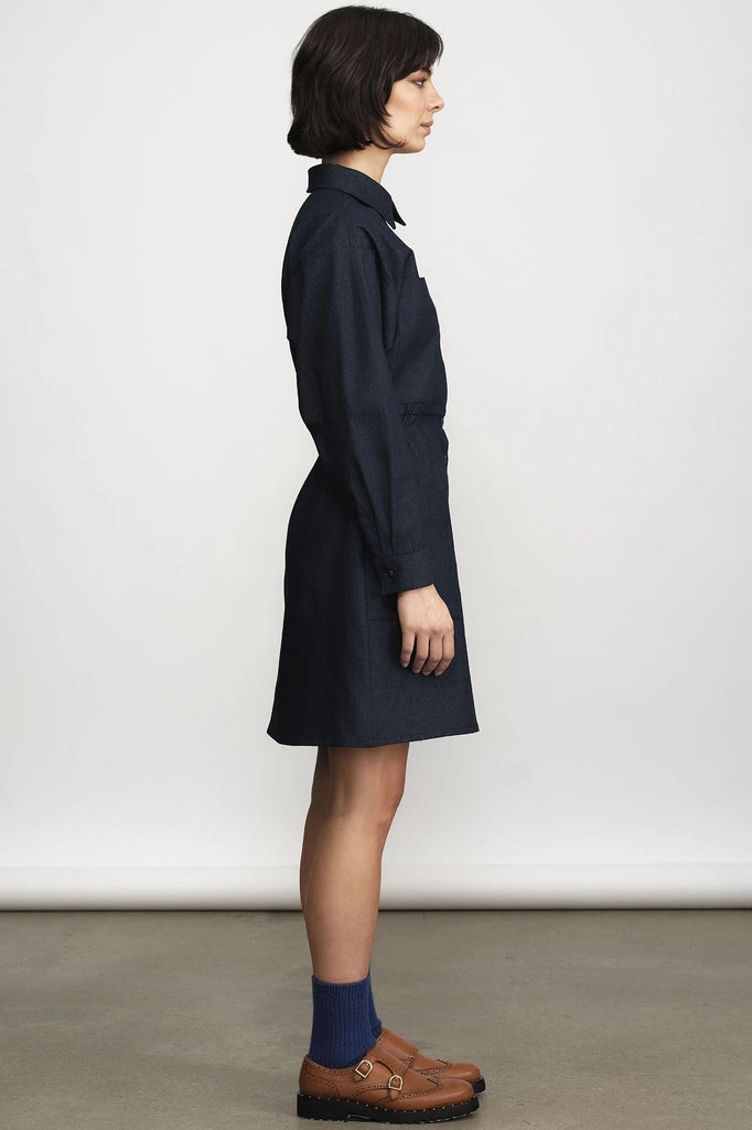 Side view of a woman in the Jennifer Glasgow Design Celeste long-sleeve shirt dress in dark denim, with navy socks and brown loafers.