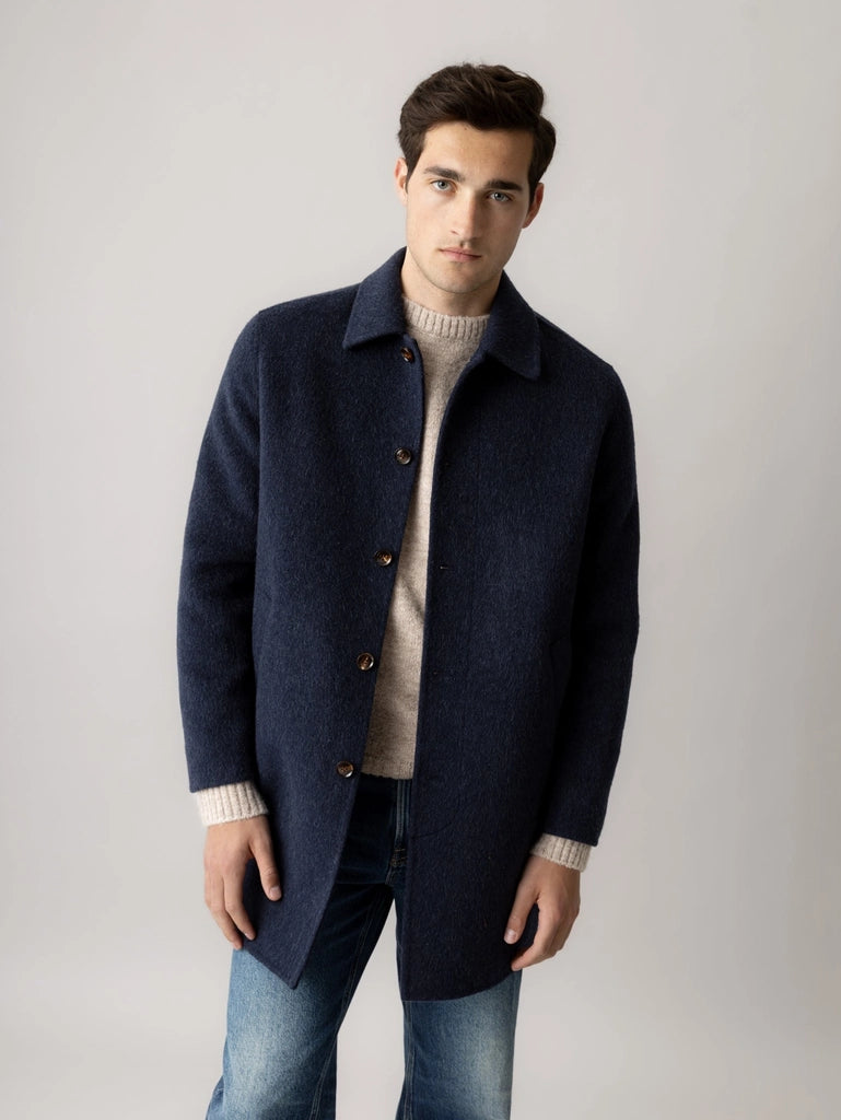 Man wearing the MOS MOSH Gallery Canada Barkley Wool Coat in salute navy, open over an oatmeal knit sweater with blue jeans, against a light grey studio background.