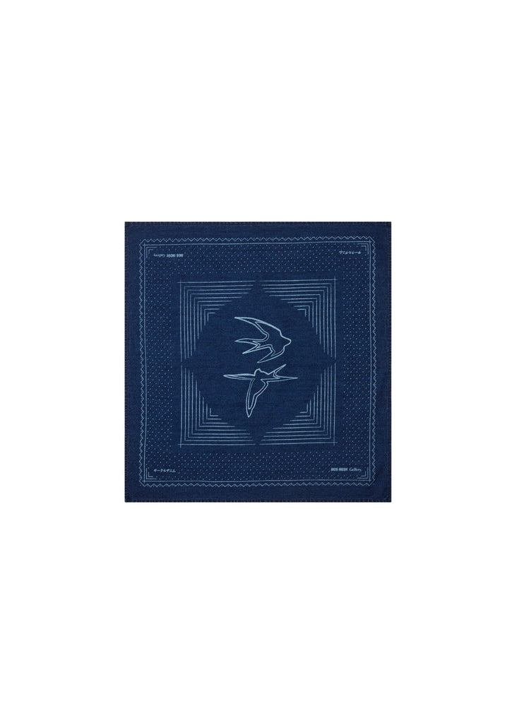 Flat lay of the MOS MOSH Gallery Canada Bird Chambray Neckerchief in indigo blue, laid out flat to show the two swallows at the centre and the geometric border, on a white background.