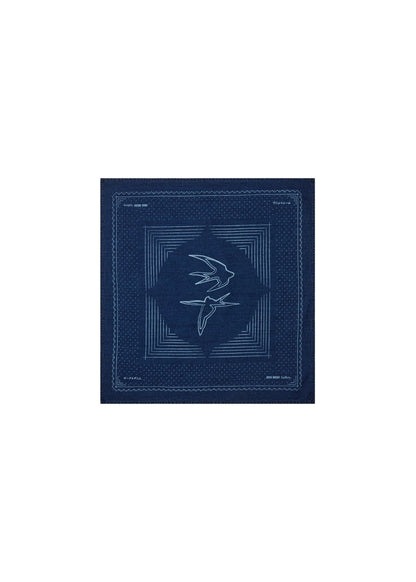 Flat lay of the MOS MOSH Gallery Canada Bird Chambray Neckerchief in indigo blue, laid out flat to show the two swallows at the centre and the geometric border, on a white background.