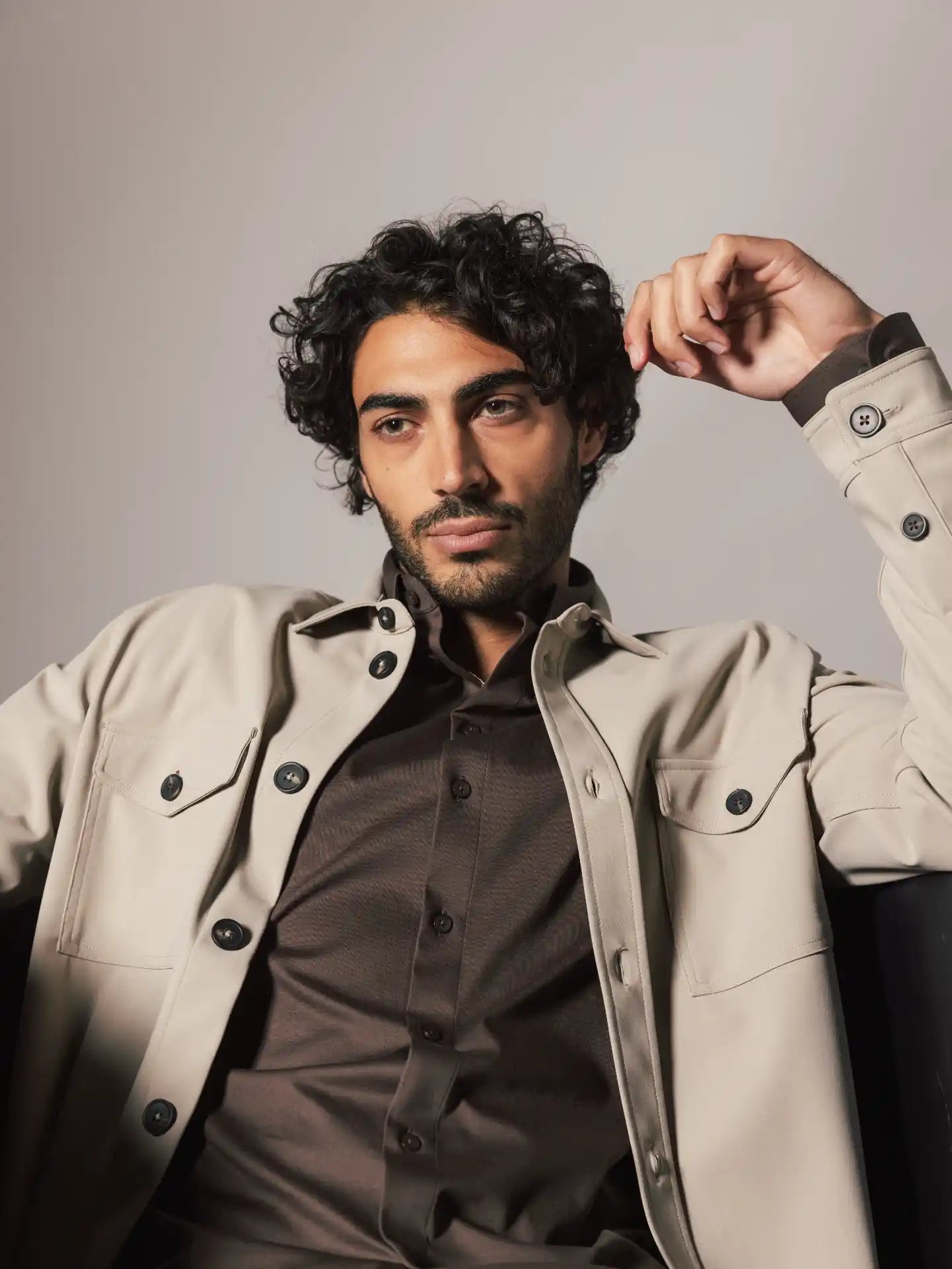 Mos Mosh Gallery beige button front overshirt with flap pockets over brown shirt on seated male model in Kelowna