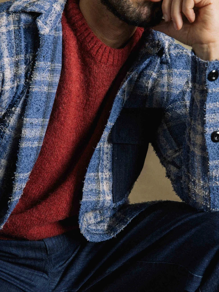 Close-up of the MOS MOSH Gallery Canada Carlos Crew Neck Knit in burnt russet, showing the brushed texture and ribbed neckline under a blue plaid overshirt.