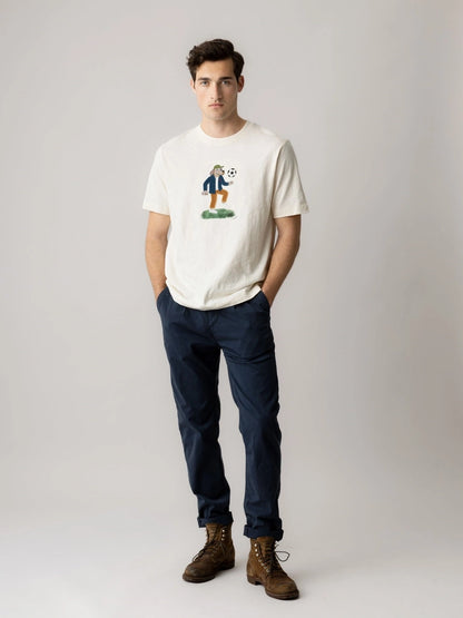 Man wearing the MOS MOSH Gallery Canada Jones All-Day Pant in Salute Navy with a white graphic tee and brown boots, against a light grey studio background.
