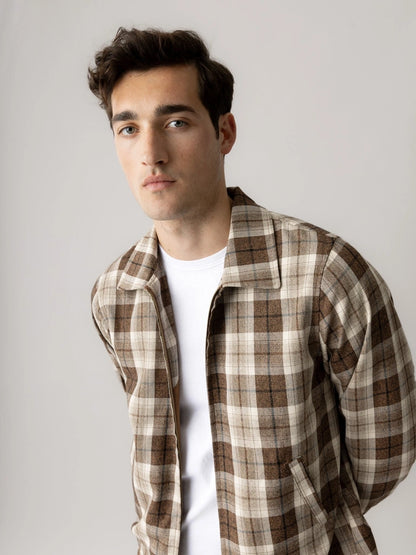 Close-up of a man wearing the MOS MOSH Gallery Canada Trossard Jacket in toffee check over a white tee, against a light grey studio background.