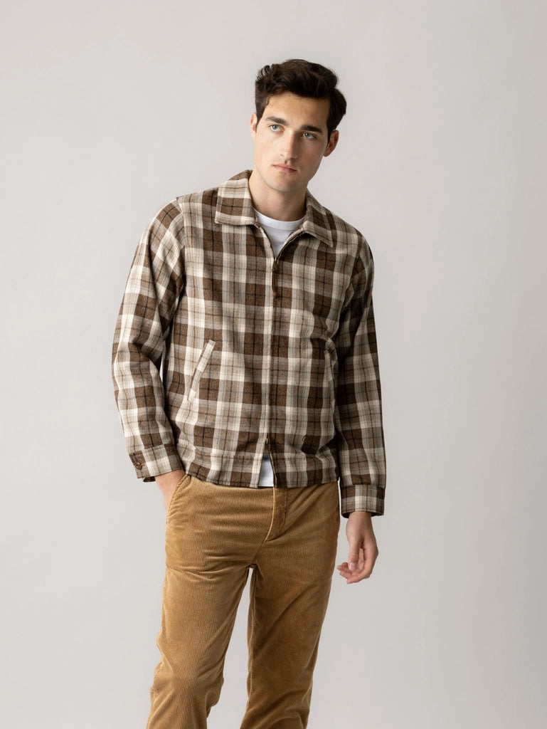 Man wearing the MOS MOSH Gallery Canada Trossard Jacket in toffee check over a white tee with tan corduroy trousers, against a light grey studio background.