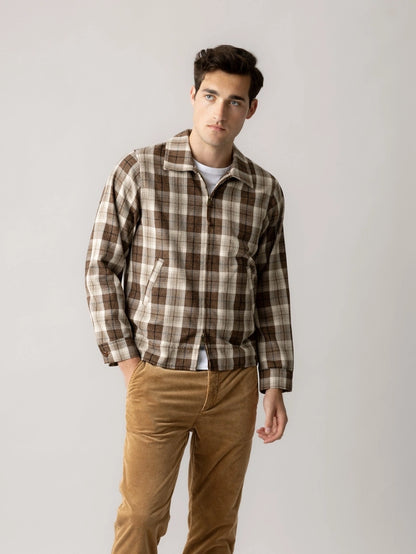 Man wearing the MOS MOSH Gallery Canada Trossard Jacket in toffee check over a white tee with tan corduroy trousers, against a light grey studio background.