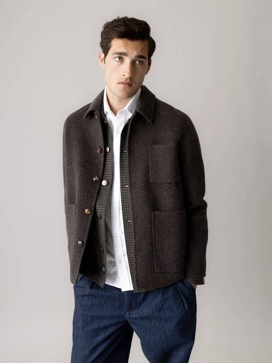 Man wearing the MOS MOSH Gallery Canada Warren Jacket in delicioso brown, open over a check overshirt and white shirt with dark denim trousers, against a light grey studio background.