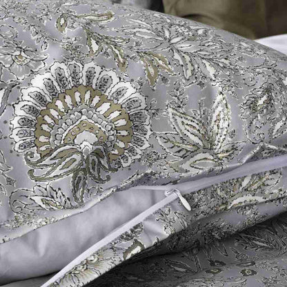 A close-up of a pillow sham with a woven floral and paisley pattern in gray, white, and muted gold, shown folded with a zipper visible.