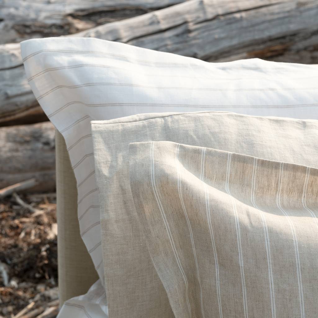 Close-up of a beige and white striped fabric with wooden logs in the background