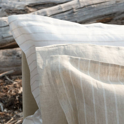 Close-up of a beige and white striped fabric with wooden logs in the background