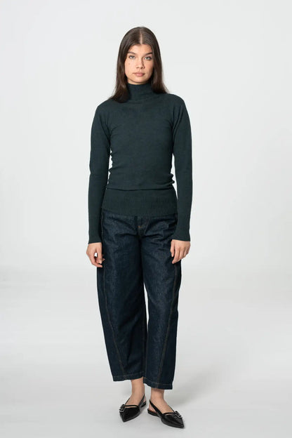 Dinadi women's merino turtleneck sweater in dark green, paired with high-waisted jeans